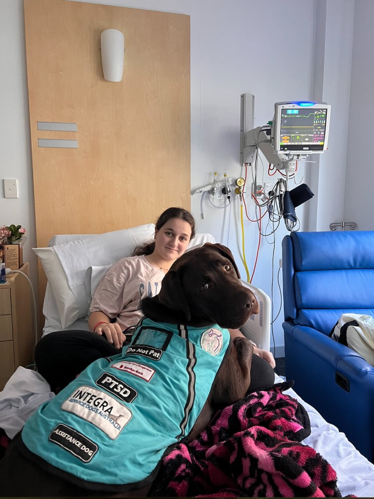 Teenage girl in a hospital bed with her service dog.