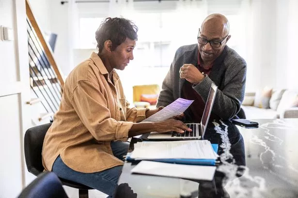 Senior couple using laptop and paying bills at home