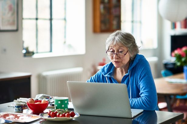 Caucasian woman in her 50s concentrating, peering at screen, working on home finances, planning for retirement