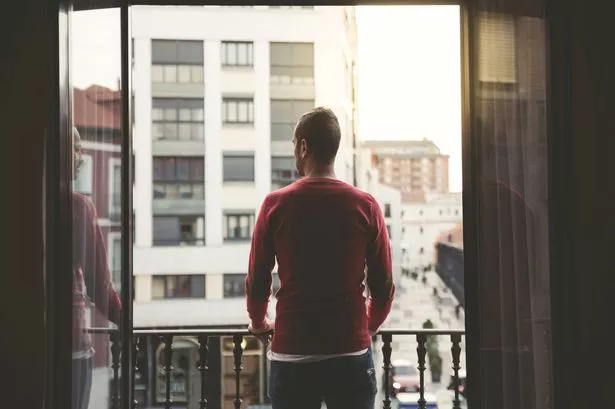 Man on a balcony in the city at sunset