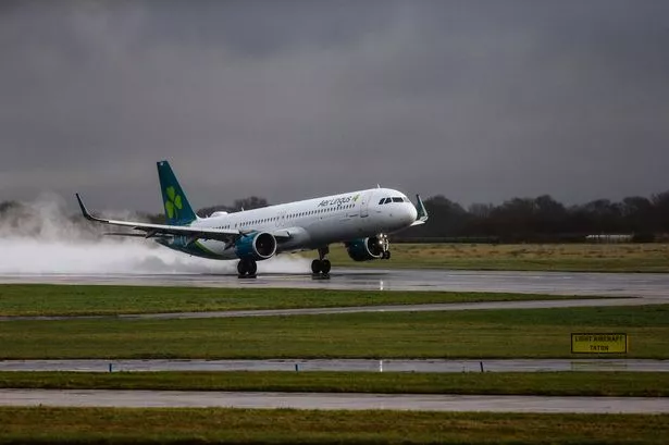An Aer Lingus flight kicks up spray as it lands at Manchester Airport