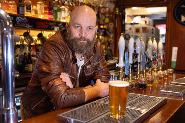 Post Office Vaults owner Mike Perkins leans on the bar with a pint of beer