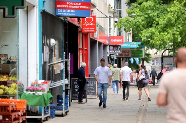 The image shows people walking up and down Commercial Street in Newport where some shops have 'for sale' signs