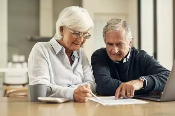 Two elderly people sat in front of a laptop, making sense of bills