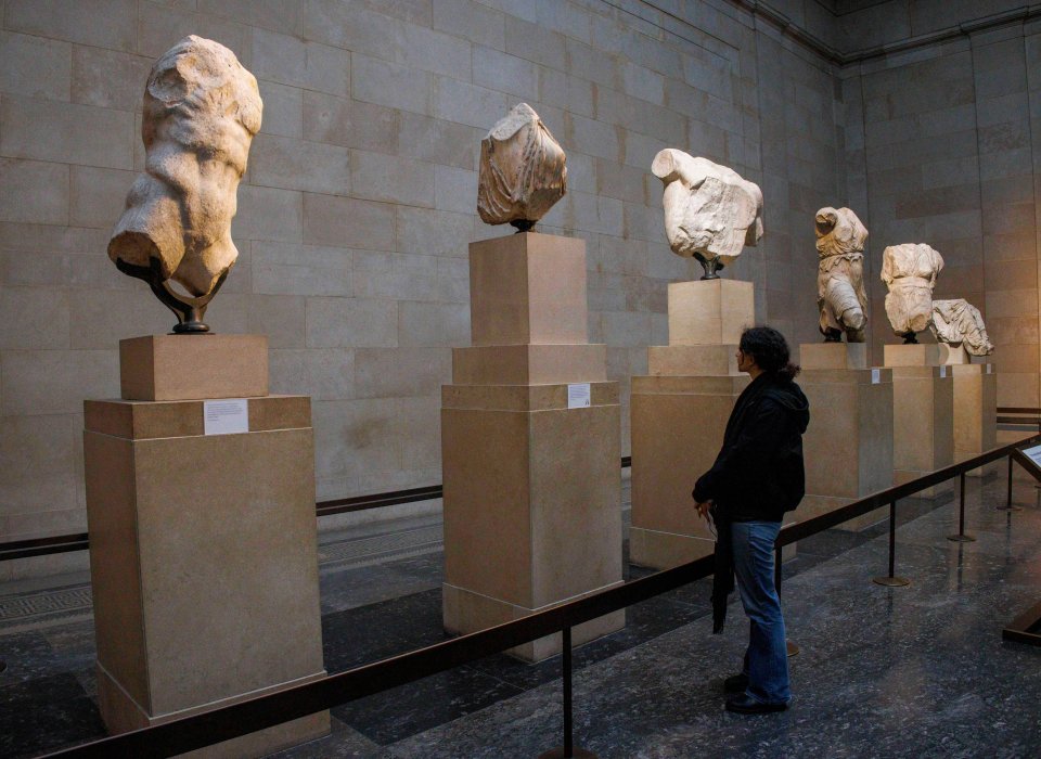 Person viewing ancient sculptures in a museum.