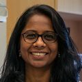 Swetha Murthy, Ph.D., has long black wavy hair and a black and white pattern shirt, eye glasses, arms folded, and smiling in her lab