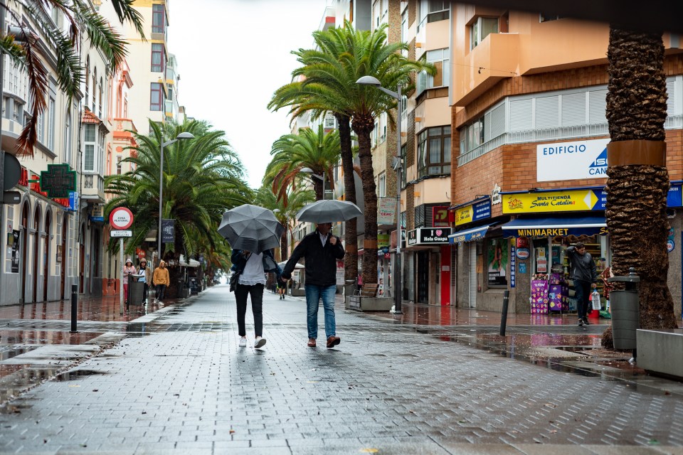 Couple sharing an umbrella on a rainy city street.