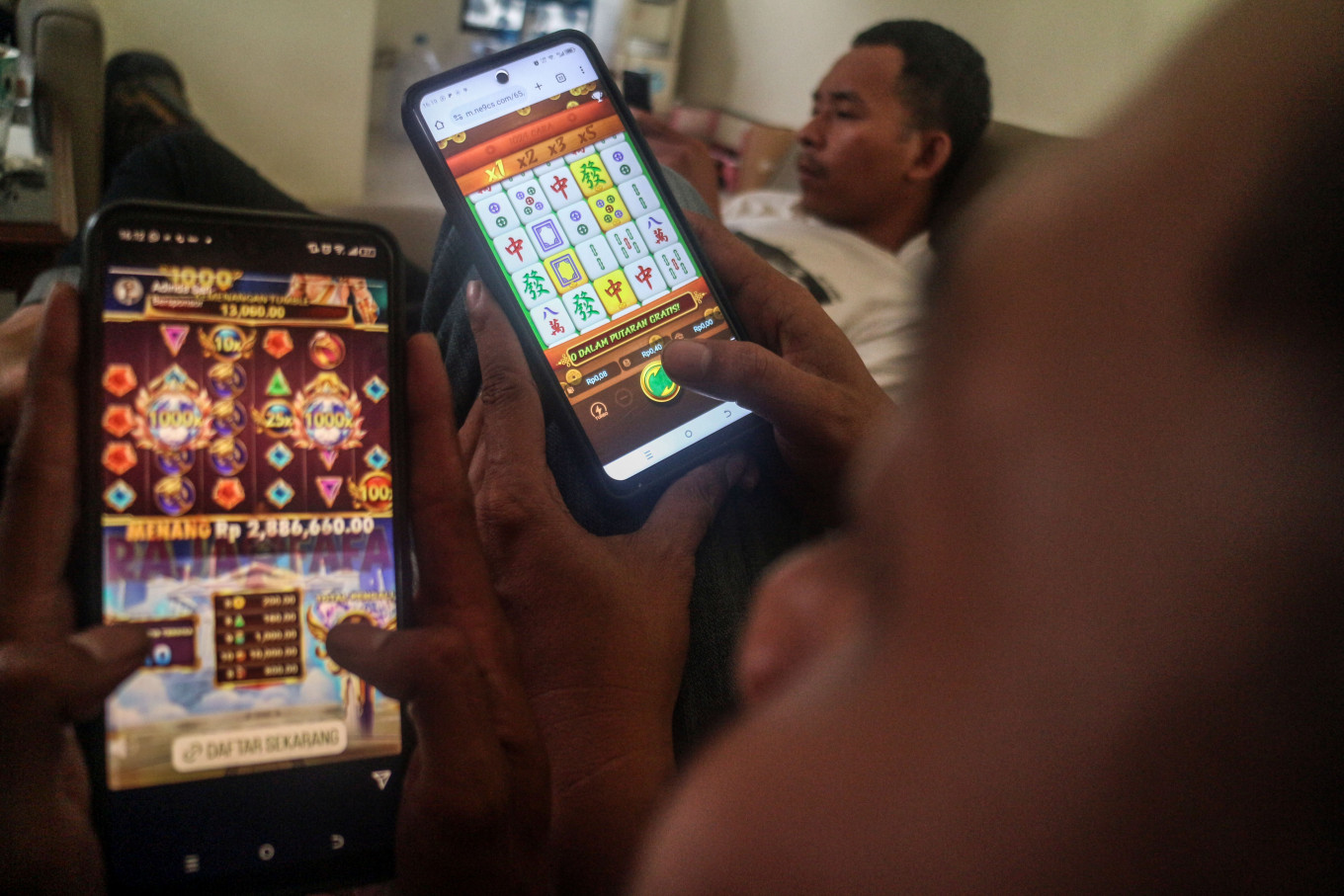 People look at online gambling websites on a smartphone in Bogor, West Java, on May 30, 2024.