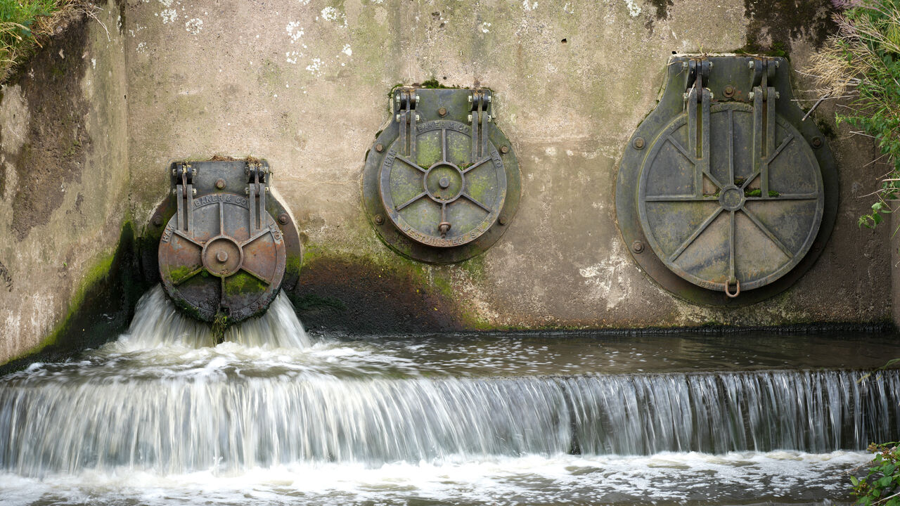 Water discharges from an outlet pipe into the River Mersey next to waste water treatment plant