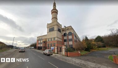 A large building with an ornate tower on the side of a road.