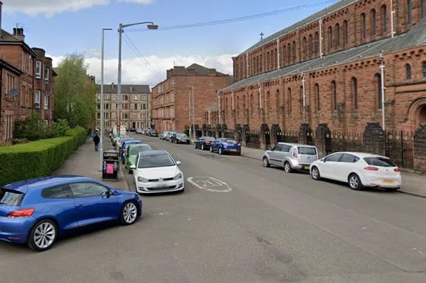 An image of a T-junction of two streets, with red-brick buildings and parked cars on either side.