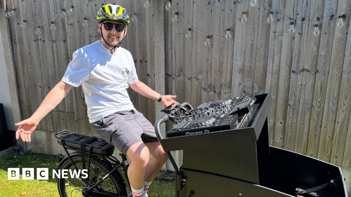 A man sitting on a bike with a DJ deck on the front of the bike.