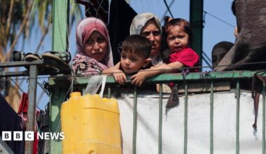 Palestinians look on at the site of an overnight Israeli strike on a school sheltering displaced families, in Gaza City