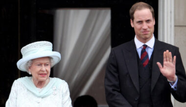 Queen Elizabeth II wears a blue jacket and matching hat and Prince William wears a suit
