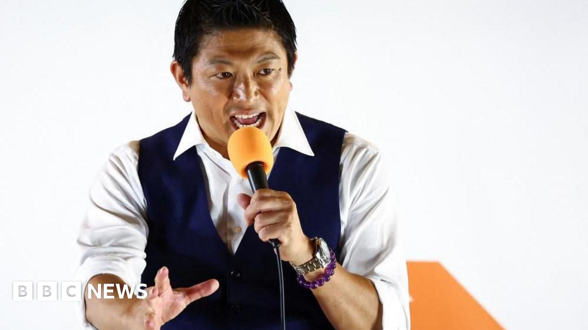 Japan's Sanseito party leader Sohei Kamiya, standing in front of his party's banner holding an orange mic, speaks to supporters on 20 July, the last day of campaigning