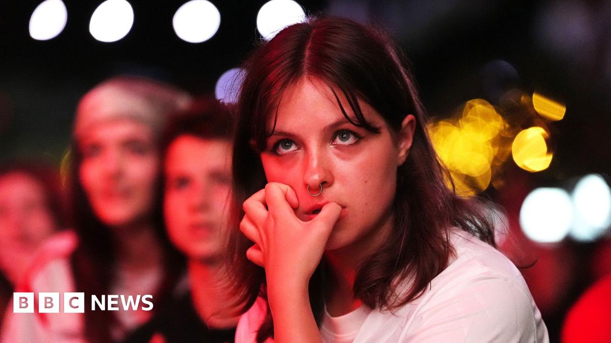 A young woman with shoulder length brown hair and a fringe bites her nails in Boxpark Croydon during the semi-final between England and Italy