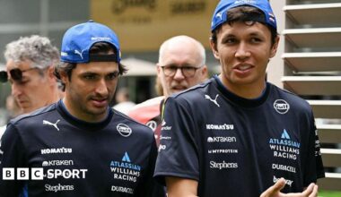 Carlos Sainz and Alex Albon in conversation at the Miami Grand Prix. Both men are wearing Williams t-shirts and caps back to front