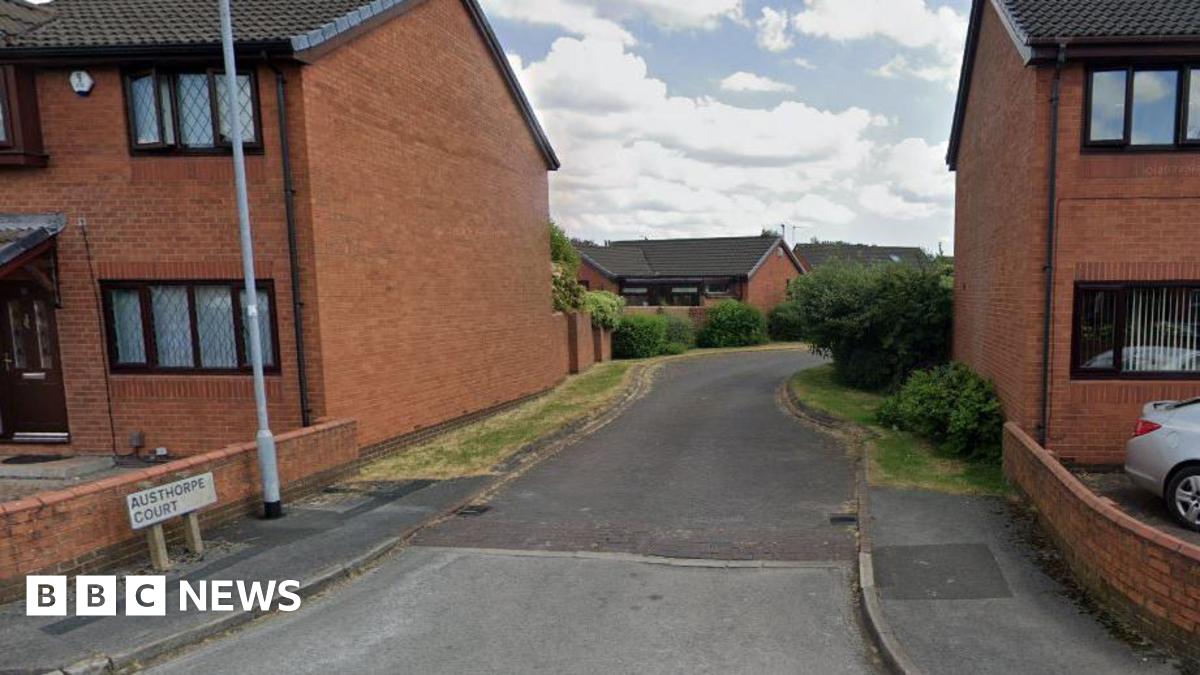 The entrance to a road of houses, with a sign at the side of the road saying Austhorpe Court