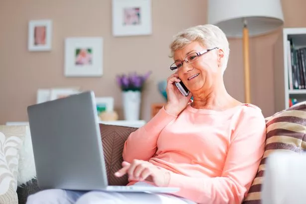 Elderly woman on laptop using internet while talking on the phone.