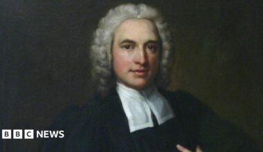 A painted portrait of Charles Wesley. He has grey curly hair and is wearing a black robe with a white cravat around his neck.