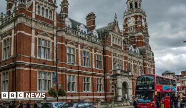 Croydon town hall, a red brick building with flags outside and a red bus at a stop.