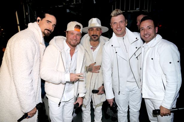 Backstreet Boys all in white outfits performing in 2022 on a stage.
