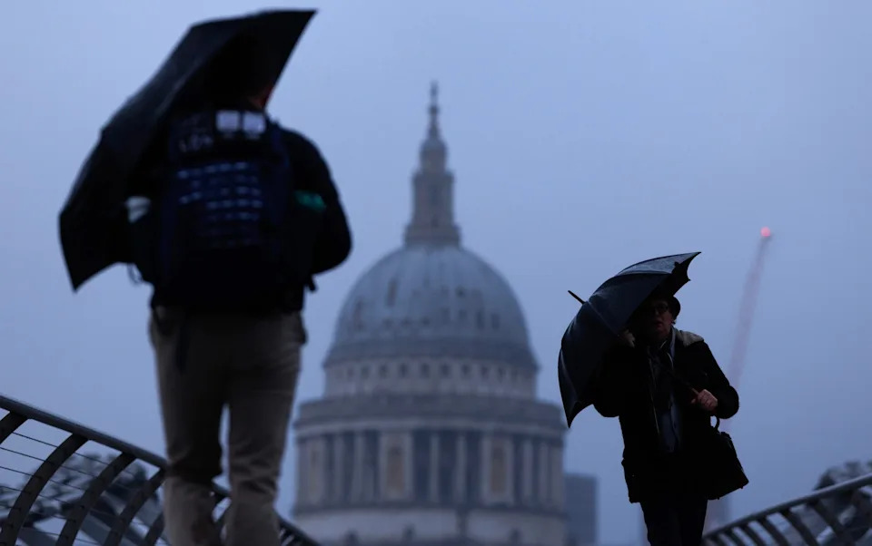 Pedestrians on Millennium Bridge holding umbrellas
