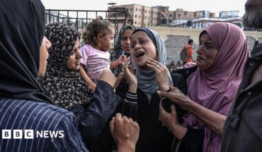 A group of women comfort another woman in the middle of their group in Khan Yunis.