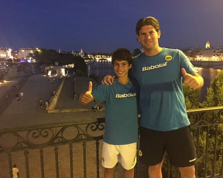 A junior Alcaraz and grown Navarro in matching tops give thumbs-up signs on a city balcony at night