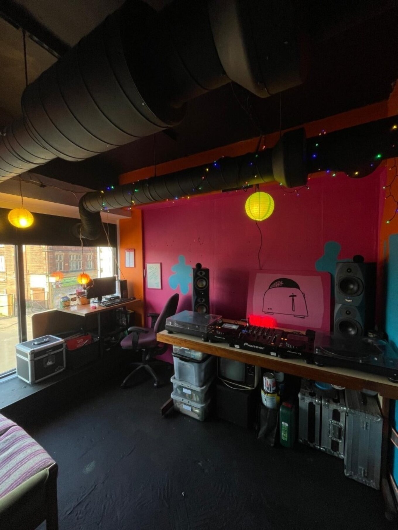 A photo of some DJ equipment including decks in front of a pink-painted wall