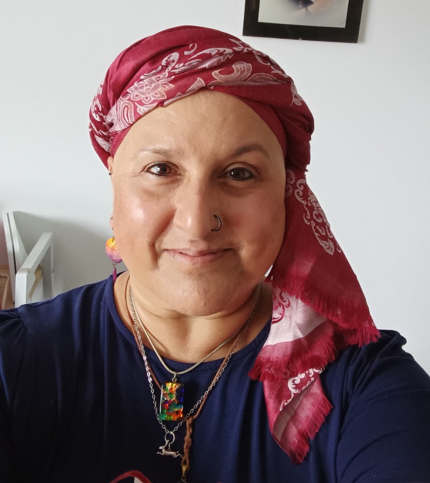 Woman wearing a headscarf and necklaces, with a framed photo in the background.