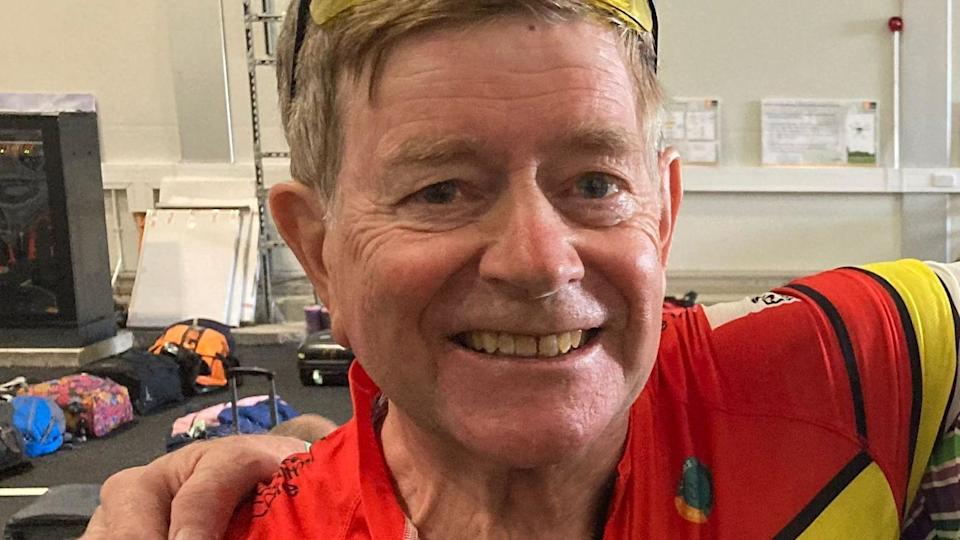 A man in a red cycling top smiling at the camera.