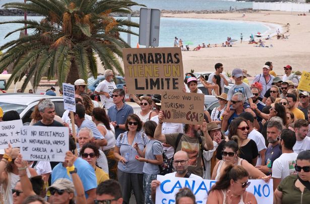 People march past a beach during a demonstration against over tourism in Fuerteventura