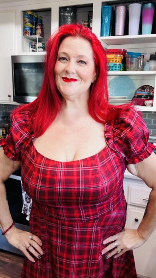 Woman with bright red hair wearing a red plaid dress.