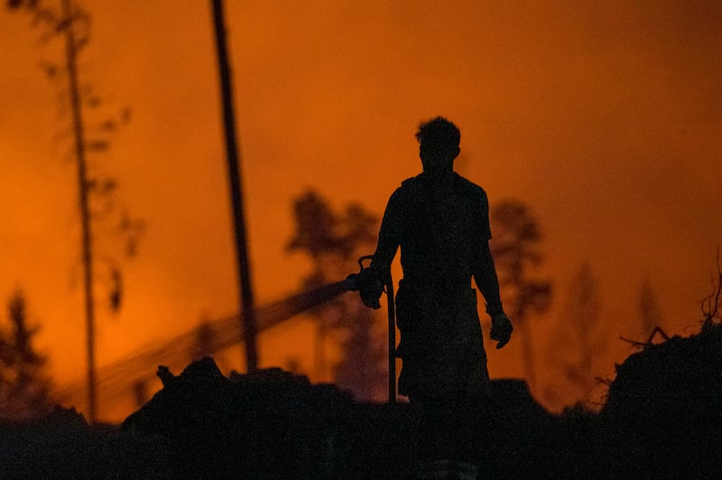 A firefighter extinguishes embers from a forest fire fanned by strong winds in Germany (Daniel Vogl/dpa via AP)