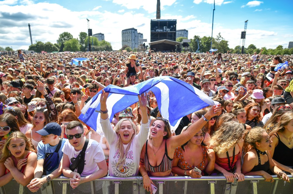 Large crowd of people at an outdoor music festival.
