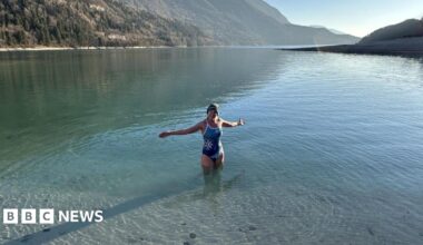 Ellie Bull swimming in a lake whilst on holiday, surrounded by mountains.