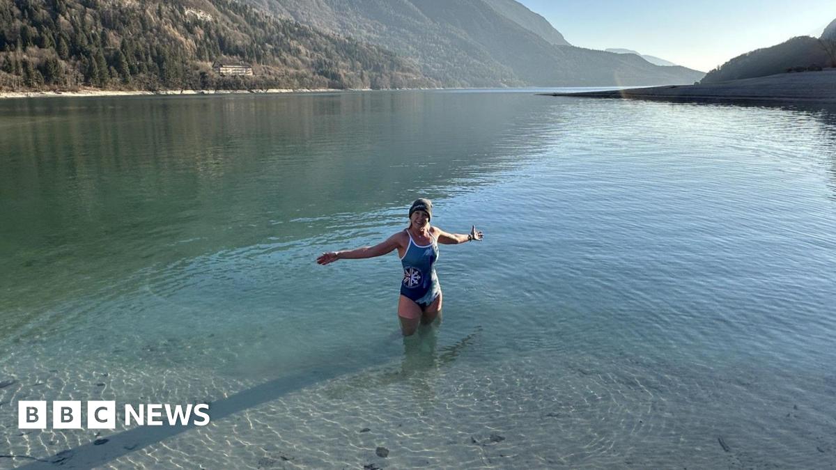 Ellie Bull swimming in a lake whilst on holiday, surrounded by mountains.