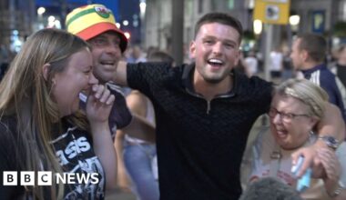 Four Oasis fans cheer in the street.