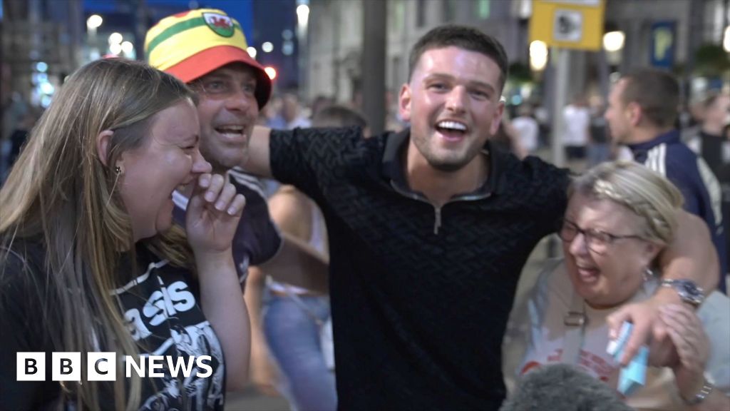Four Oasis fans cheer in the street.