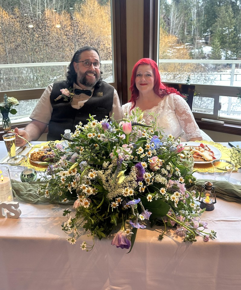 A bride and groom sit at their wedding reception table.