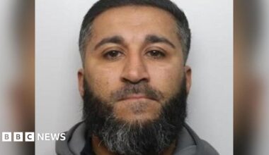 Mugshot of rapist Amar Khan, 42, who has black hair and a black and grey beard.