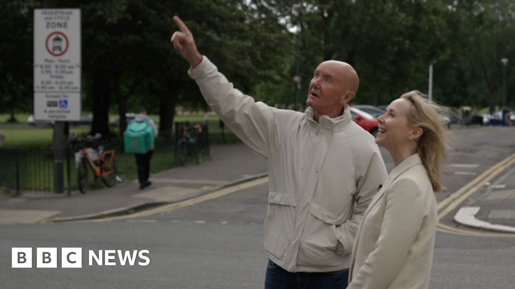 Irvine Welsh and Katie Razzall in Leith. He is pointing up at a building.