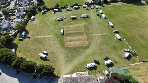 Lee Garlick A picture of the vans parked on the large grass field. A number of vans can Be seen parked on the grass in the distance. 