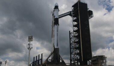 dark clouds in the sky above a white rocket upright on a launch pad