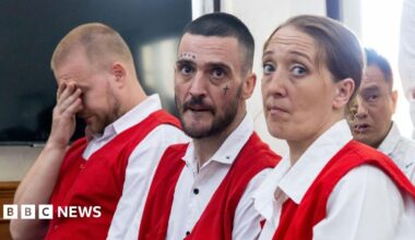 Phineas Float, Jon Collyer and Lisa Stocker (left to right) are accused of drug offences in Bali. They are wearing distinctive white and red prison uniforms. Collyer has facial tattoos.