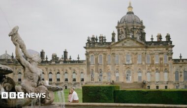 Castle Howard. A large stately home. A couple sit on the edge of a fountain in front of the property.