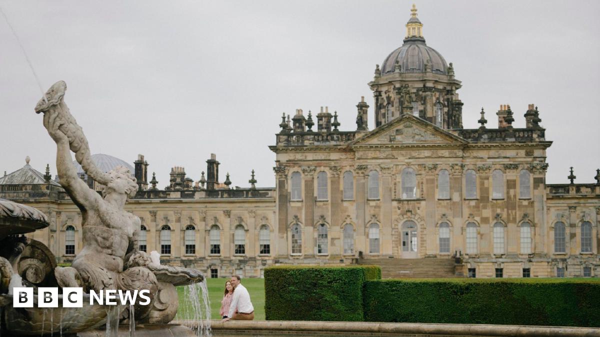 Castle Howard. A large stately home. A couple sit on the edge of a fountain in front of the property.