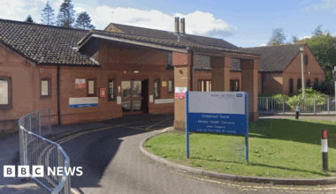 The entrance to Wedgwood House. A brown-bricked building with an NHS blue and white sign outside.