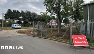 A view of the Wheatley Sewage Treatment Works site where a tank is parked and can be seen behind a metal fencing. There is a red sign for "Works access".